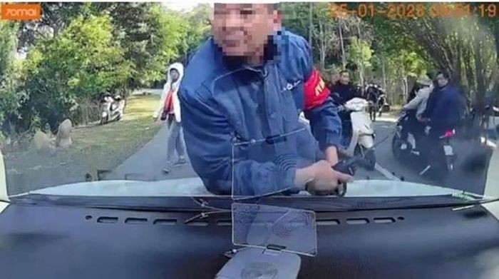 Hình ảnh nhân viên an ninh nhảy lên nắp ca pô ô tô của khách du lịch (Ảnh cắt từ clip)