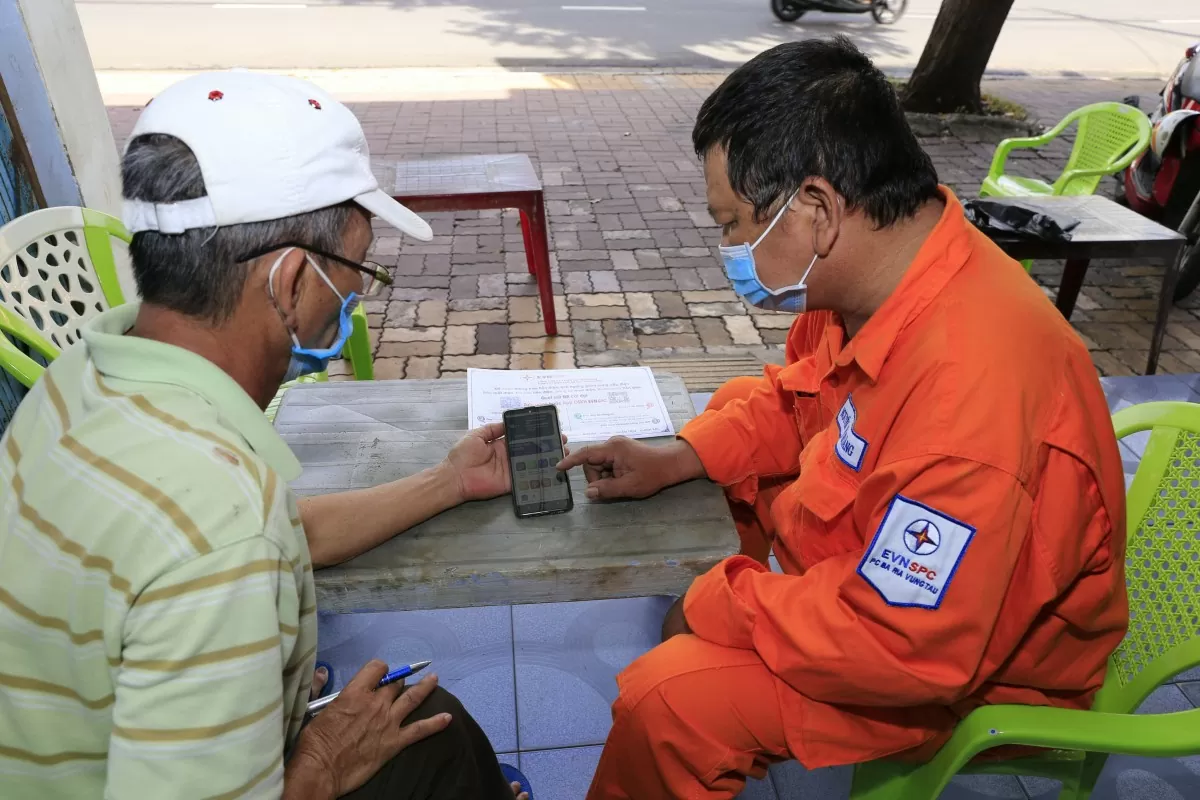 Nhân viên Điện lực Bà Rịa - Vũng Tàu hướng dẫn khách hàng cài đặt ứng dụng thanh toán điện tử.