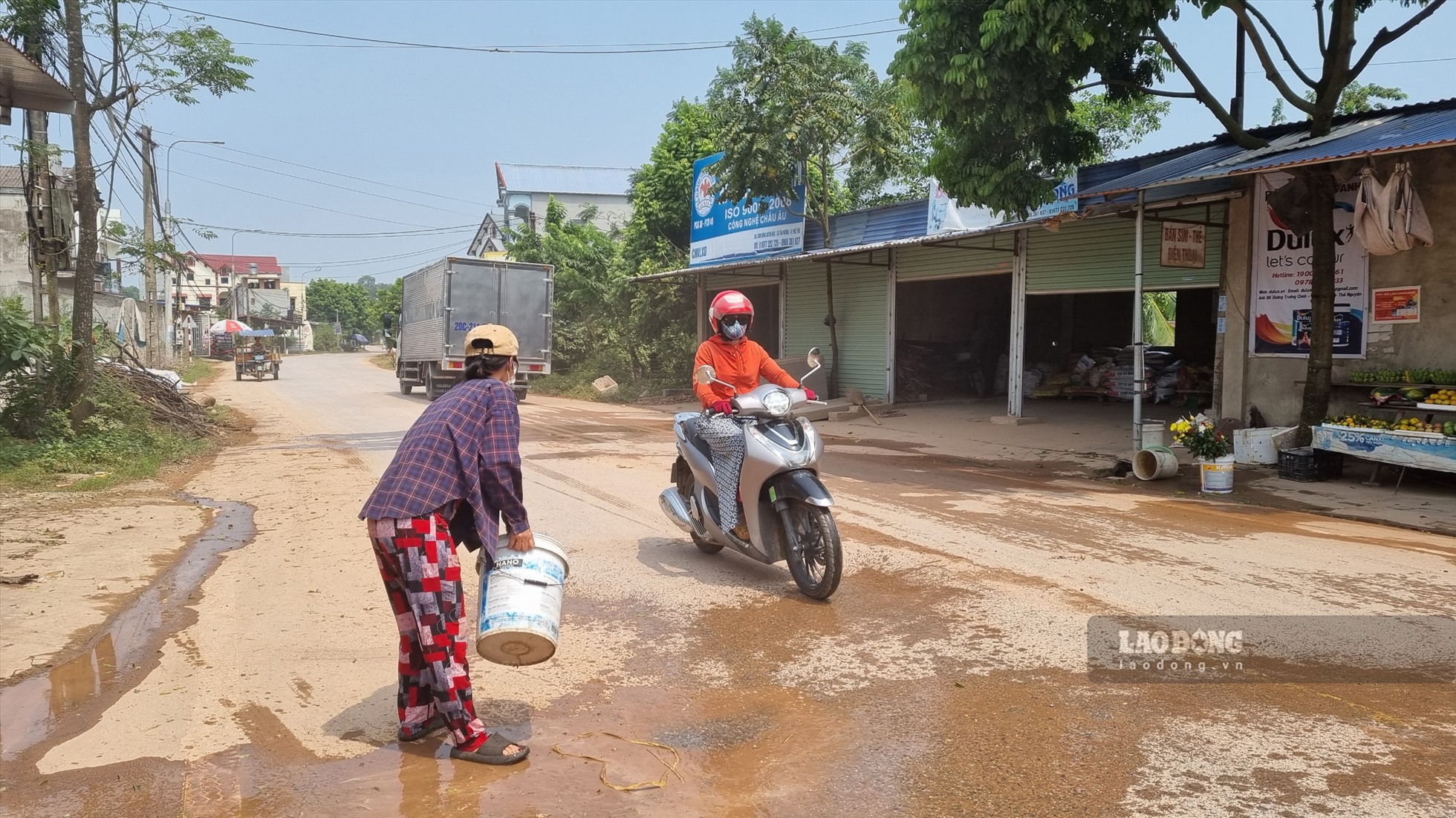 Bà Thắm thường xuyên phải tưới nước để hạn chế bụi từ đoàn xe chở đất liên tục ra vào.