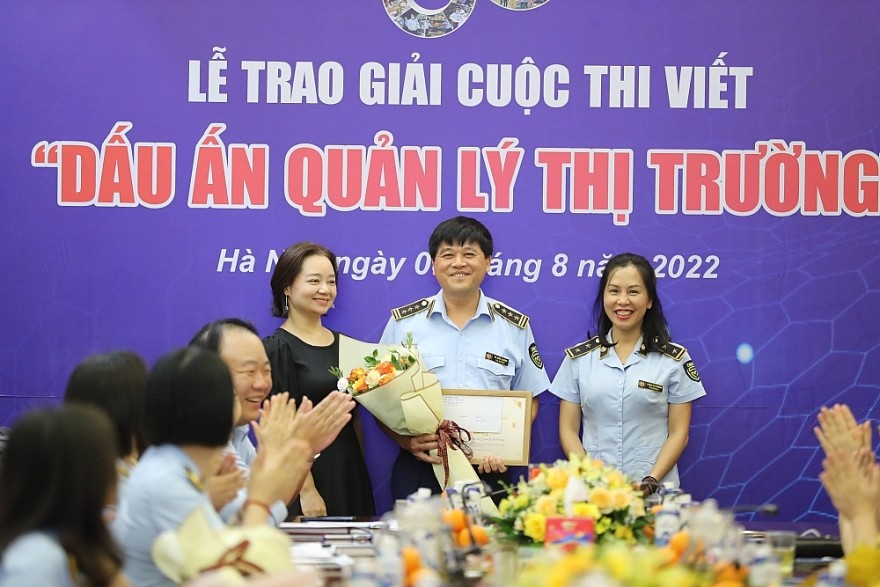 Đại diện Ban Giám khảo - bà Nguyễn Thị Lâm Giang - Chánh Văn phòng Bộ Công Thương trao hoa và Giấy chứng nhận cho các tác giả có tác phẩm đạt Giải C trong lực lượng QLTT